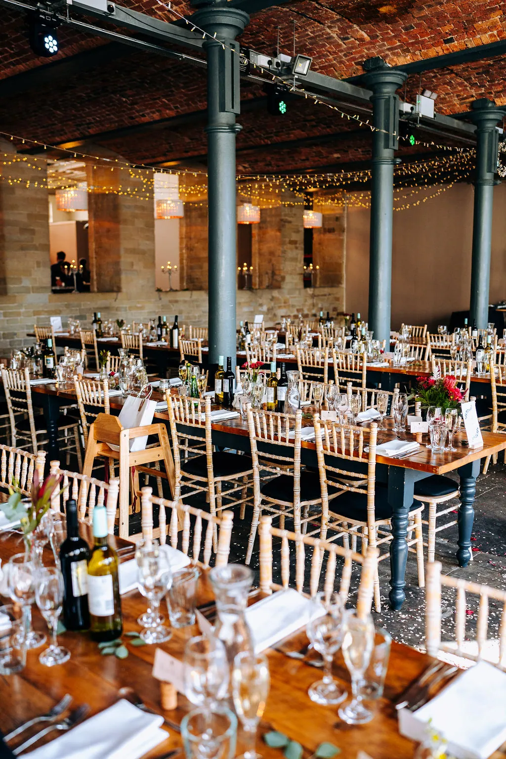 The vaulted red-brick ceiling and cast-iron columns of the hall at The Arches, long tables dressed for a wedding breakfast
