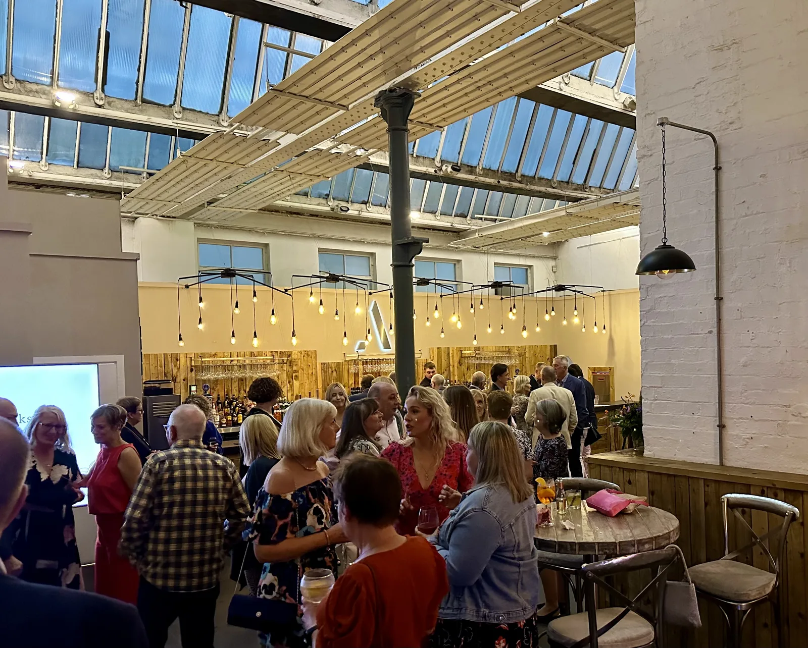 Guests mingling with drinks at an event in the light-filled hall