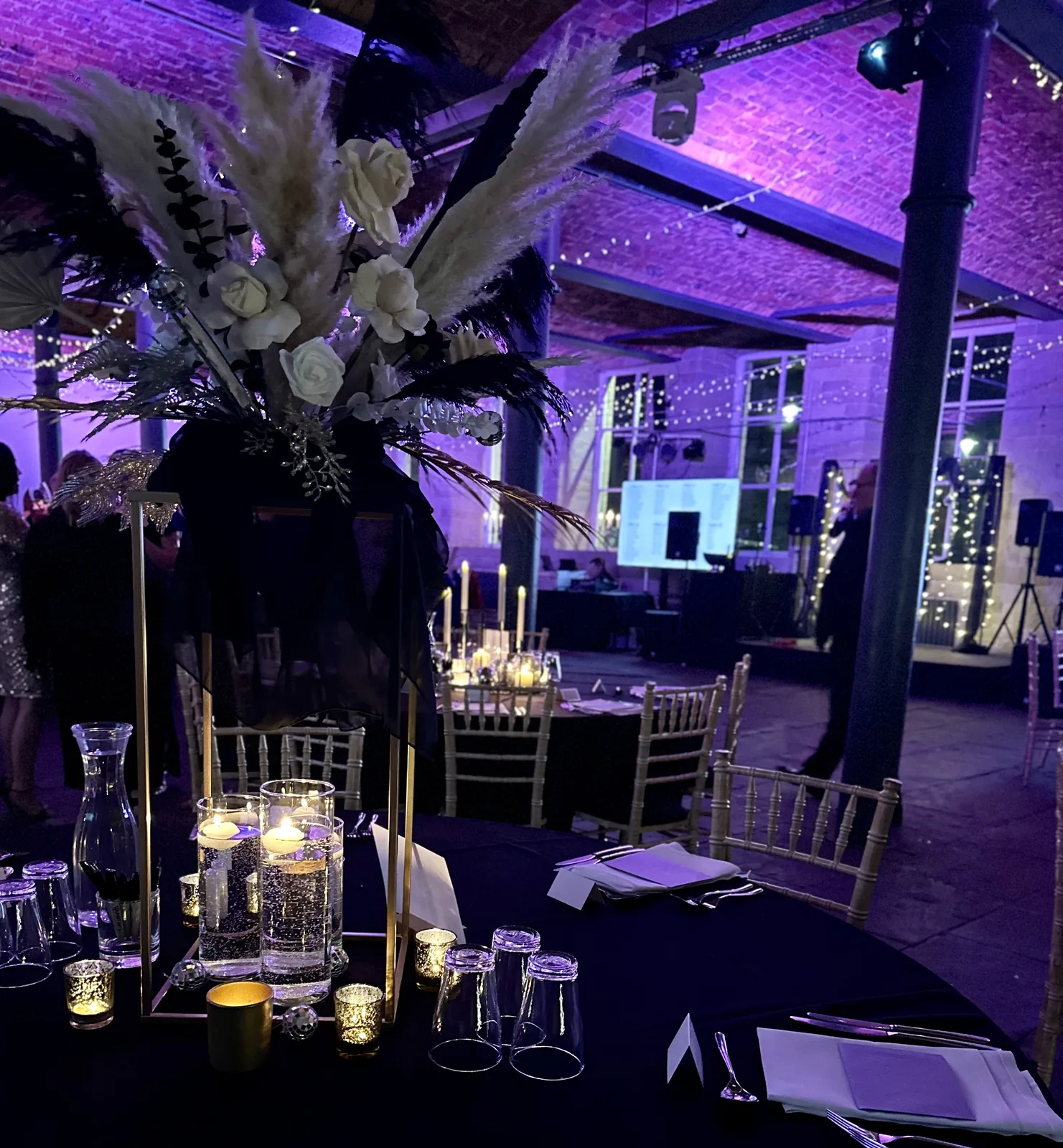 A private party at The Arches with tall feather centrepieces under purple lighting