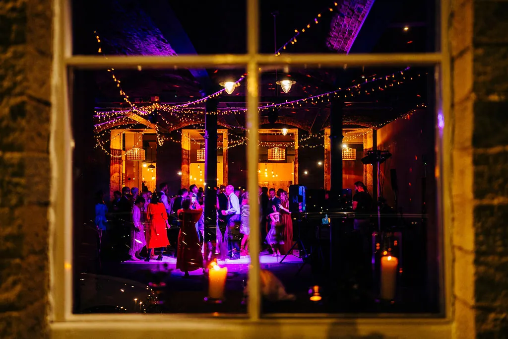 The Arches lit up at night, seen through a tall arched mill window